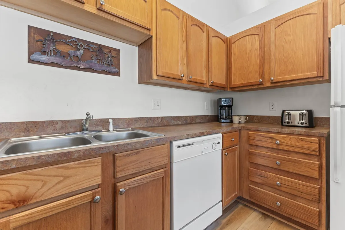 A functional kitchen area with modern appliances, stylish wooden cabinets, and wall art. The space is well-lit and designed for socializing, meal prepping, or hosting, supporting both daily routines and extended stays.