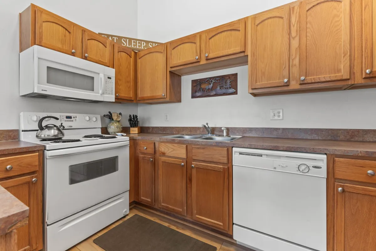 This image features a bright, functional kitchen area with modern appliances and ample wooden cabinetry. The cabinetry and counter space suggest plenty of storage for guests on extended stays, while the inviting layout creates a sense of homeliness.